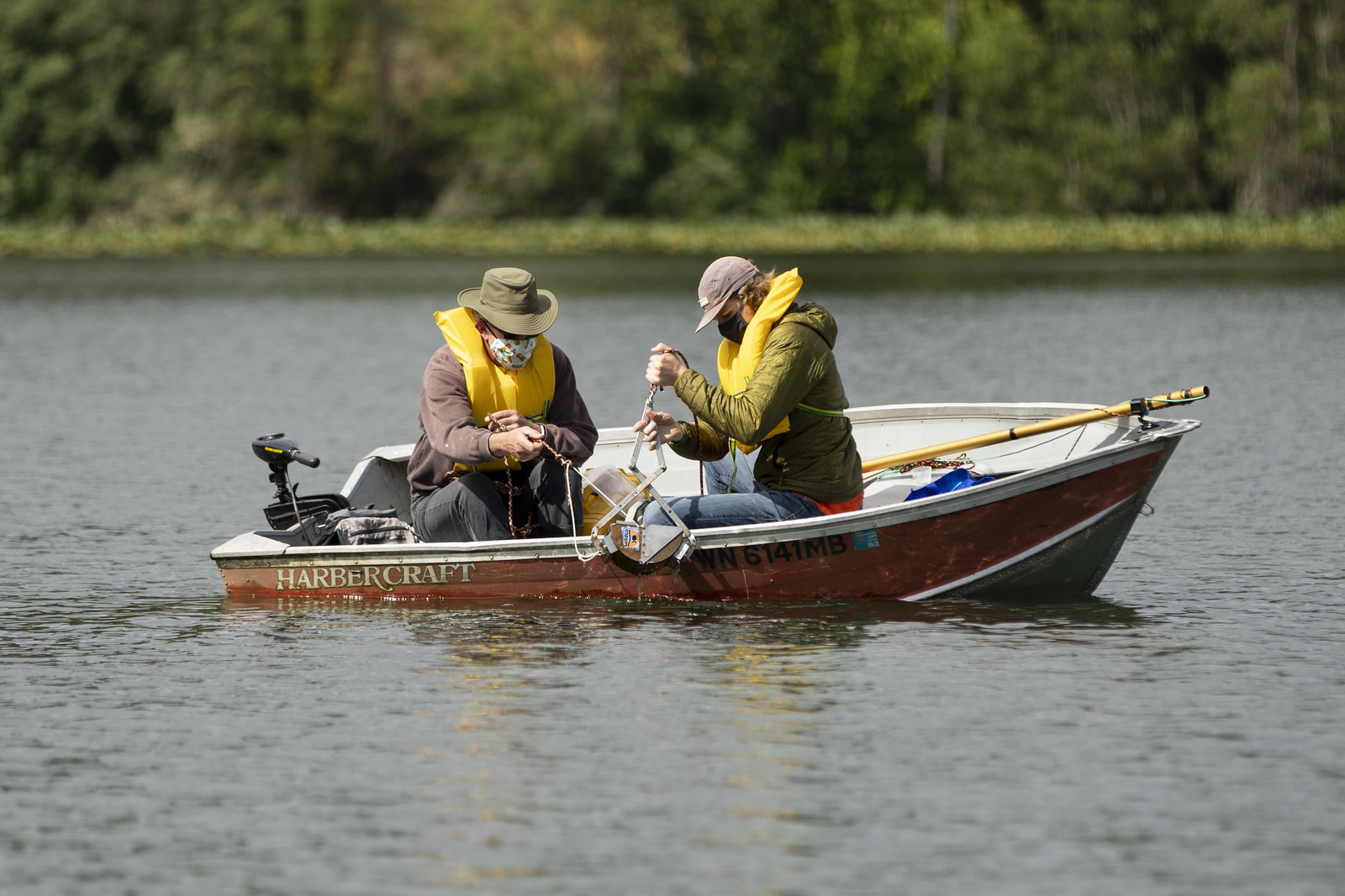 Two people using equipment in a boat on a lake