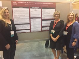 Three people standing beside an educational poster