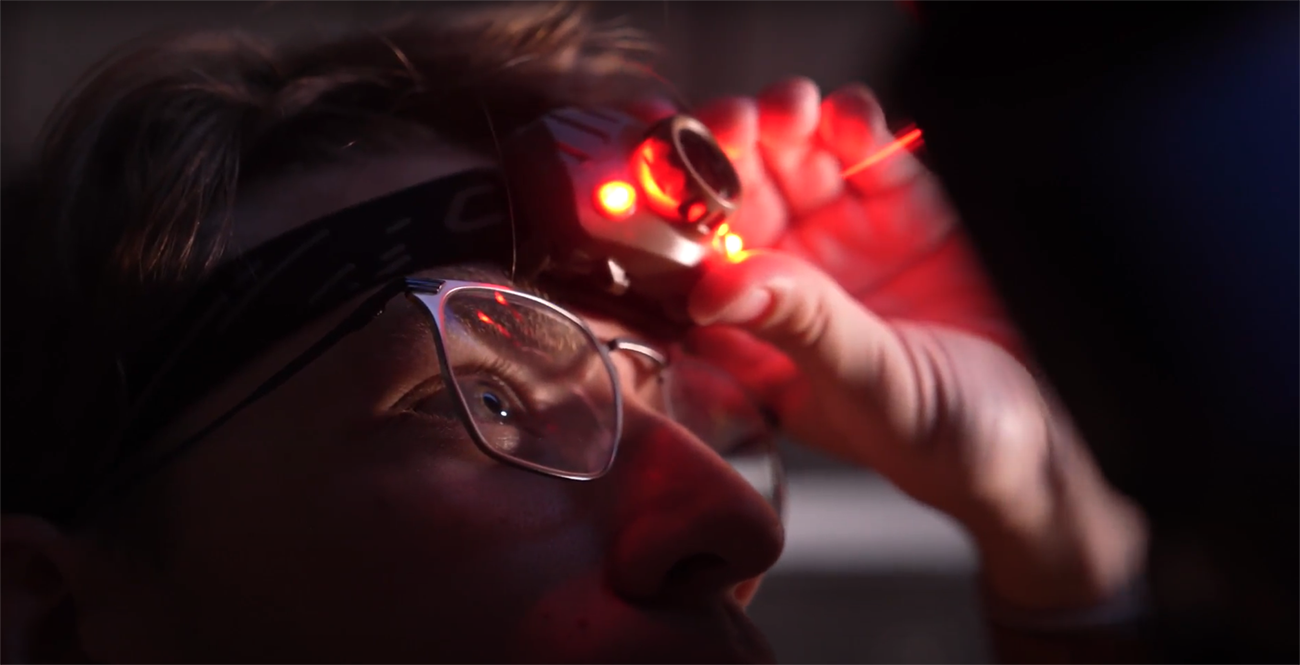 Austin Glock uses a red head lamp to make adjustments in the university observatory.