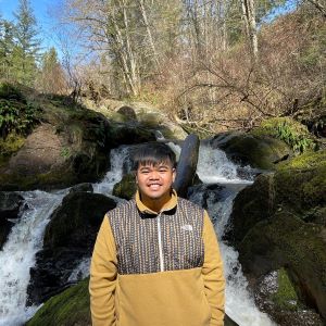 Public Health student Jansen Dacquel standing by a small waterfall.