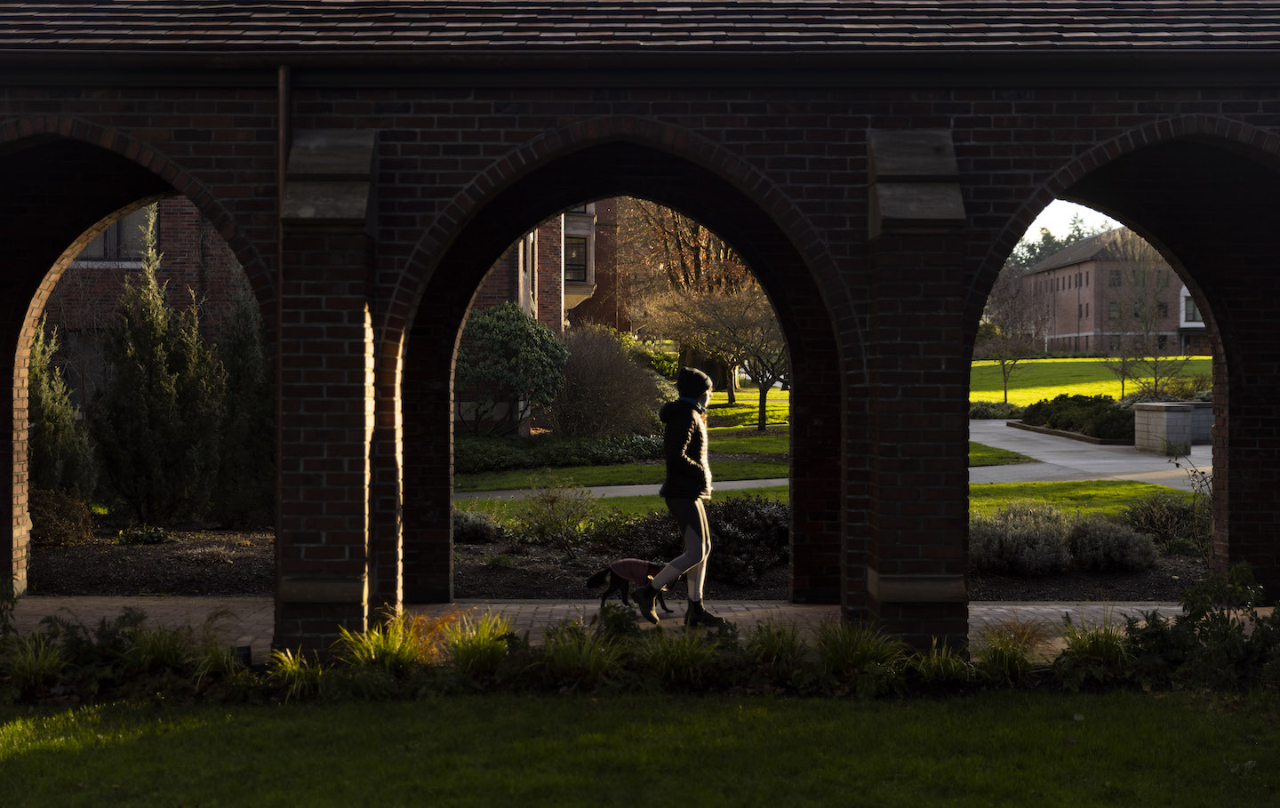 Student walking through the arches attached to Jones and Howarth hall. 