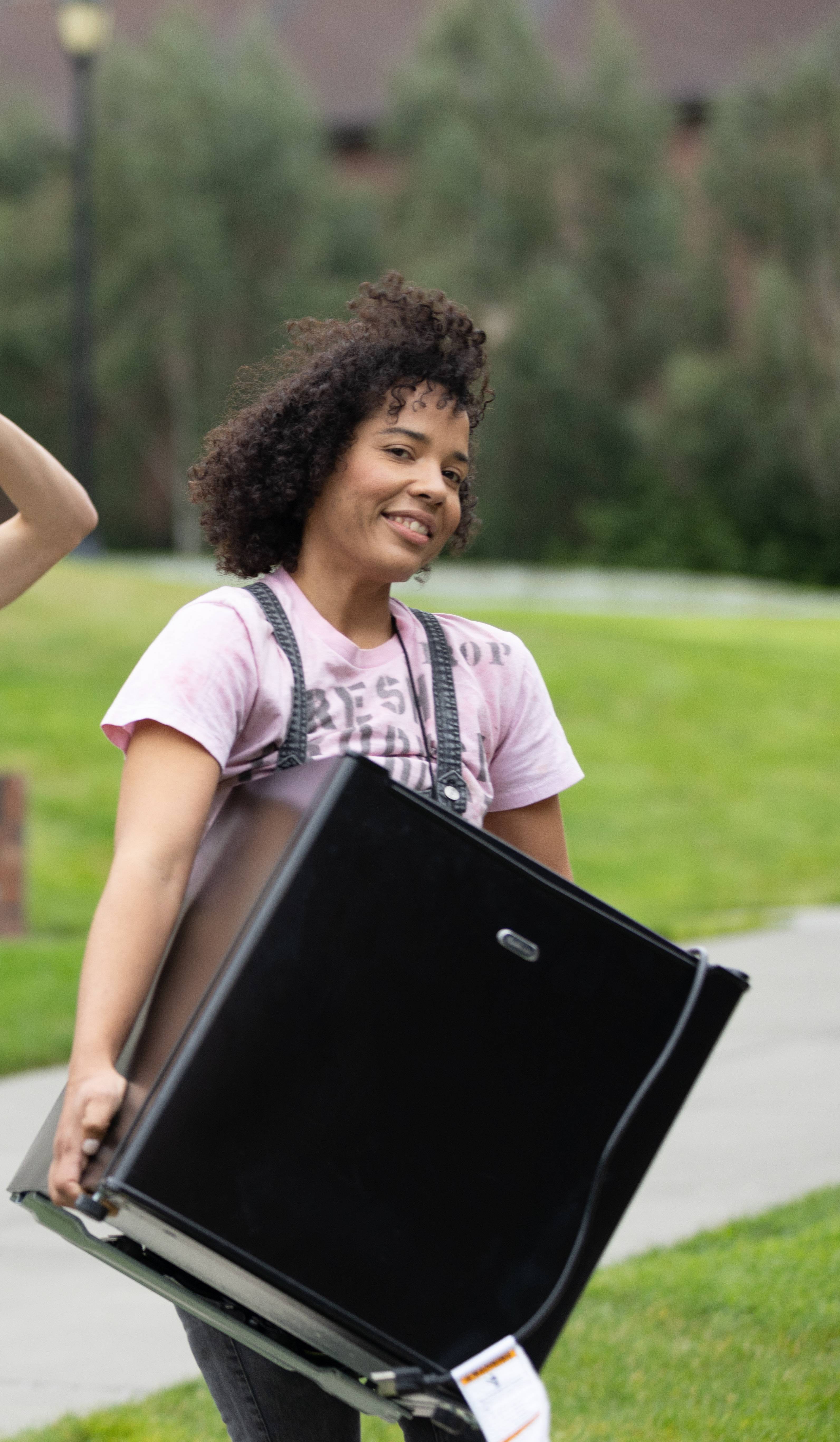 A student moves a mini-fridge into the residence hall.