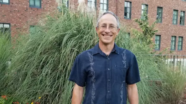 Dr. Peter Hodum standing outside in front of a tall bush.