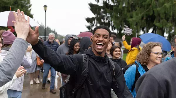 Student giving someone a high five with a smiling laugh.