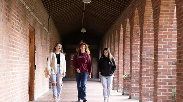 Three students walking through the covered walkway joining Jones and Howarth Halls.