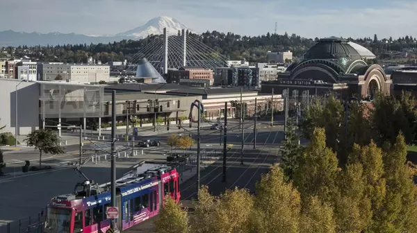 A light rail train in a city with a snow-capped mountain in the background.