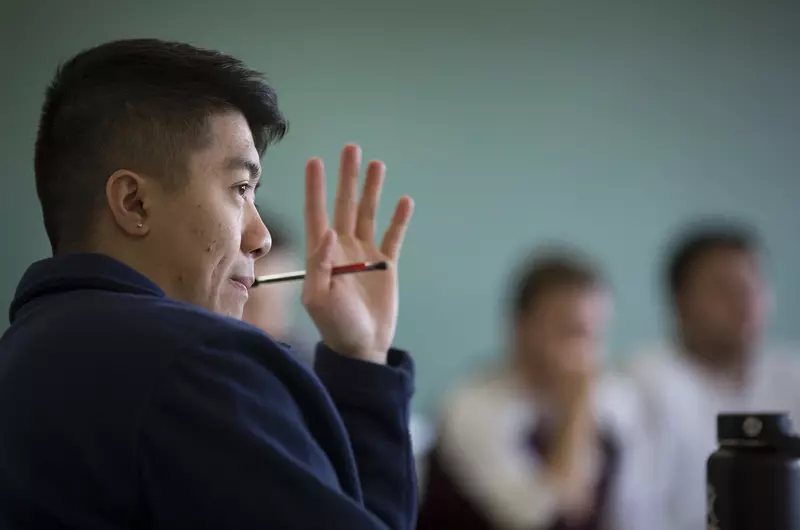 A student raises his hand to ask a question in class.