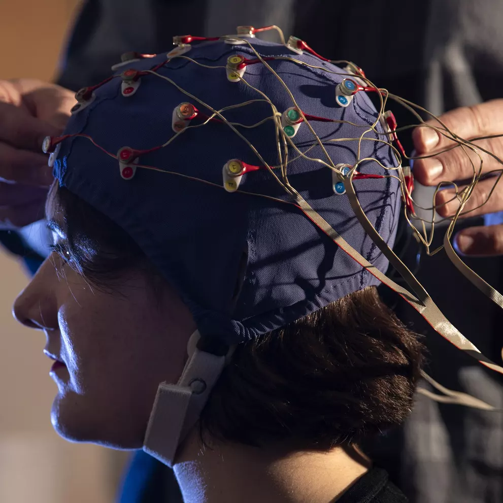 Student taking part in a study with an electrode cap on their head