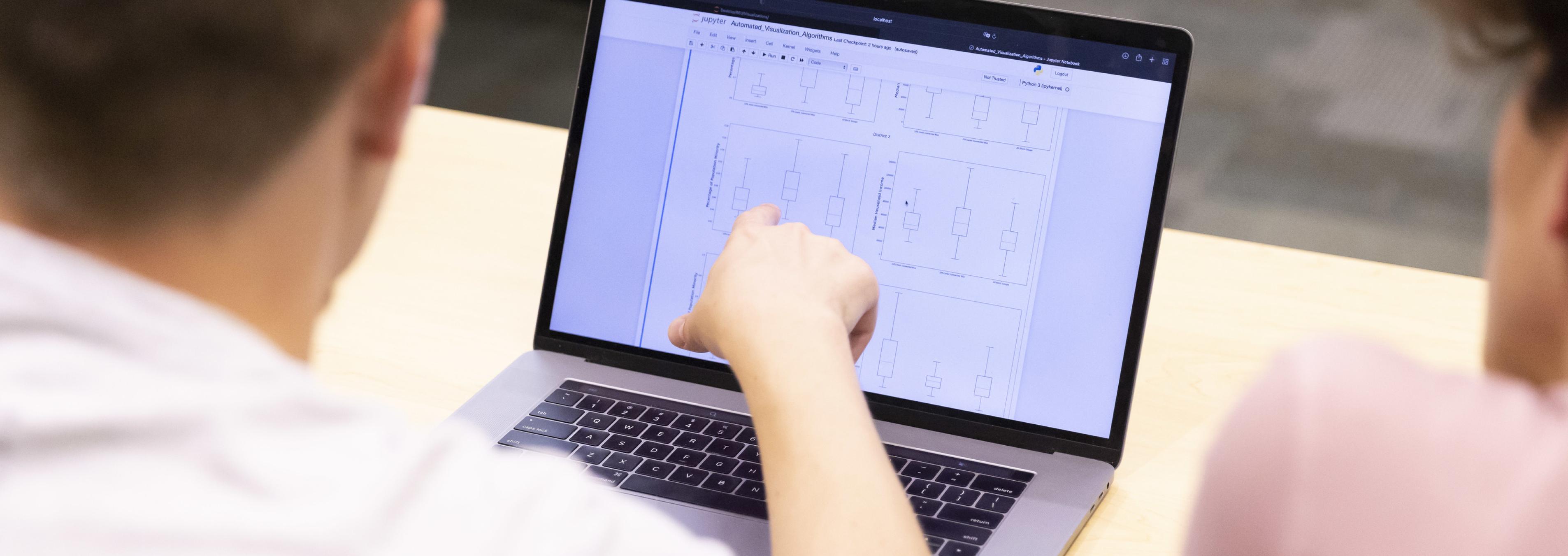 Two students look at data on a laptop.