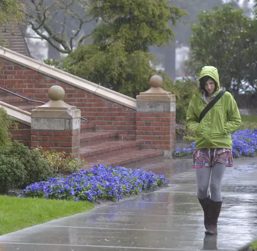 A student walks on campus in the rain.