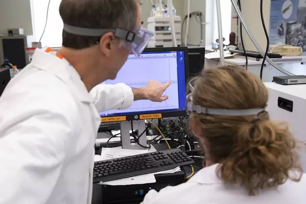 A professor guides a student doing research.