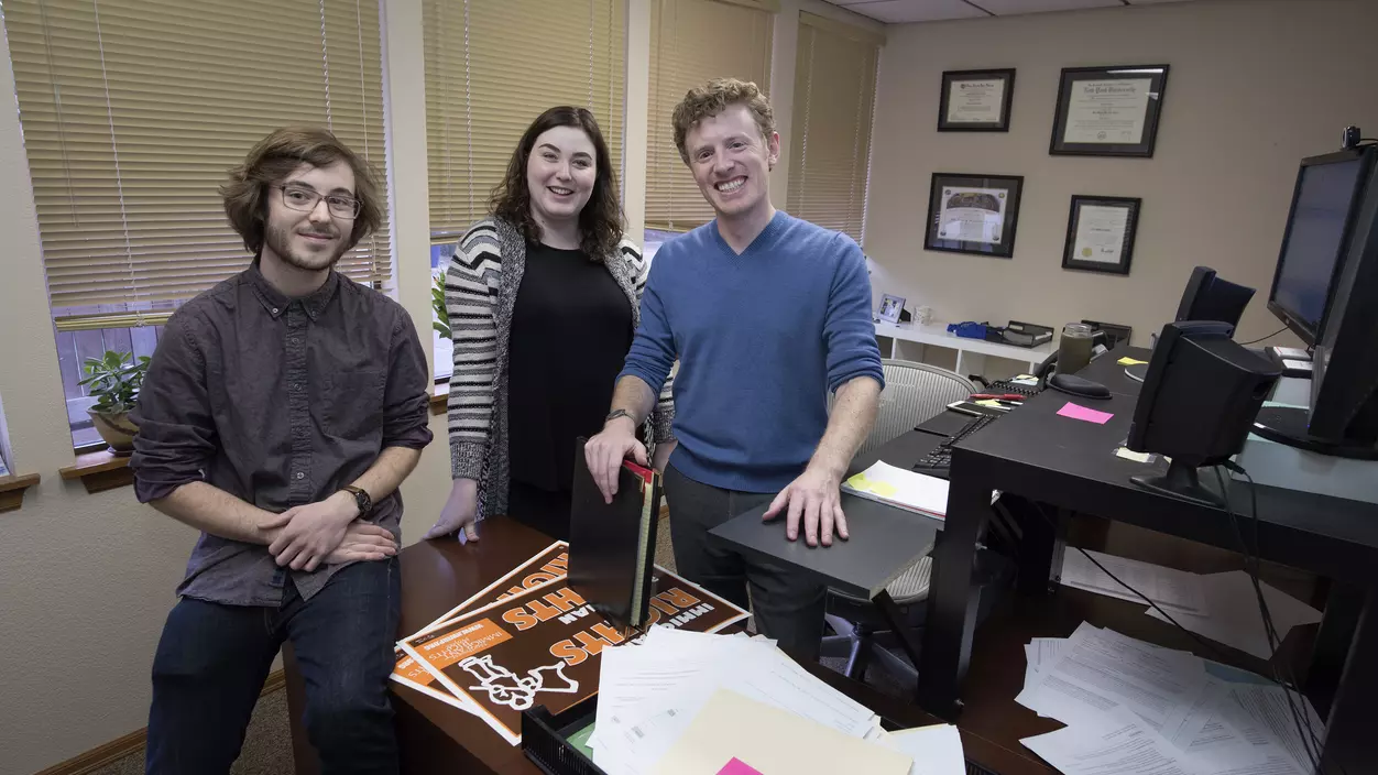 Three people smiling in an office