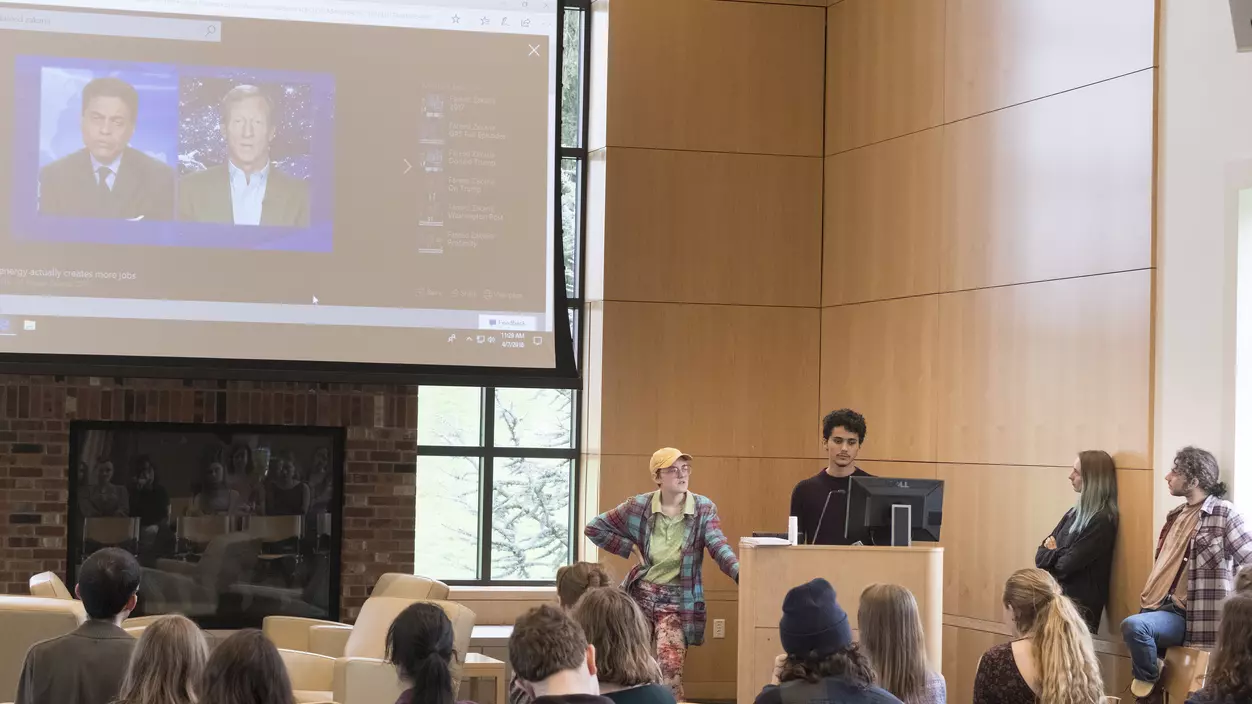 Two people standing at a podium and giving a presentation to an audience