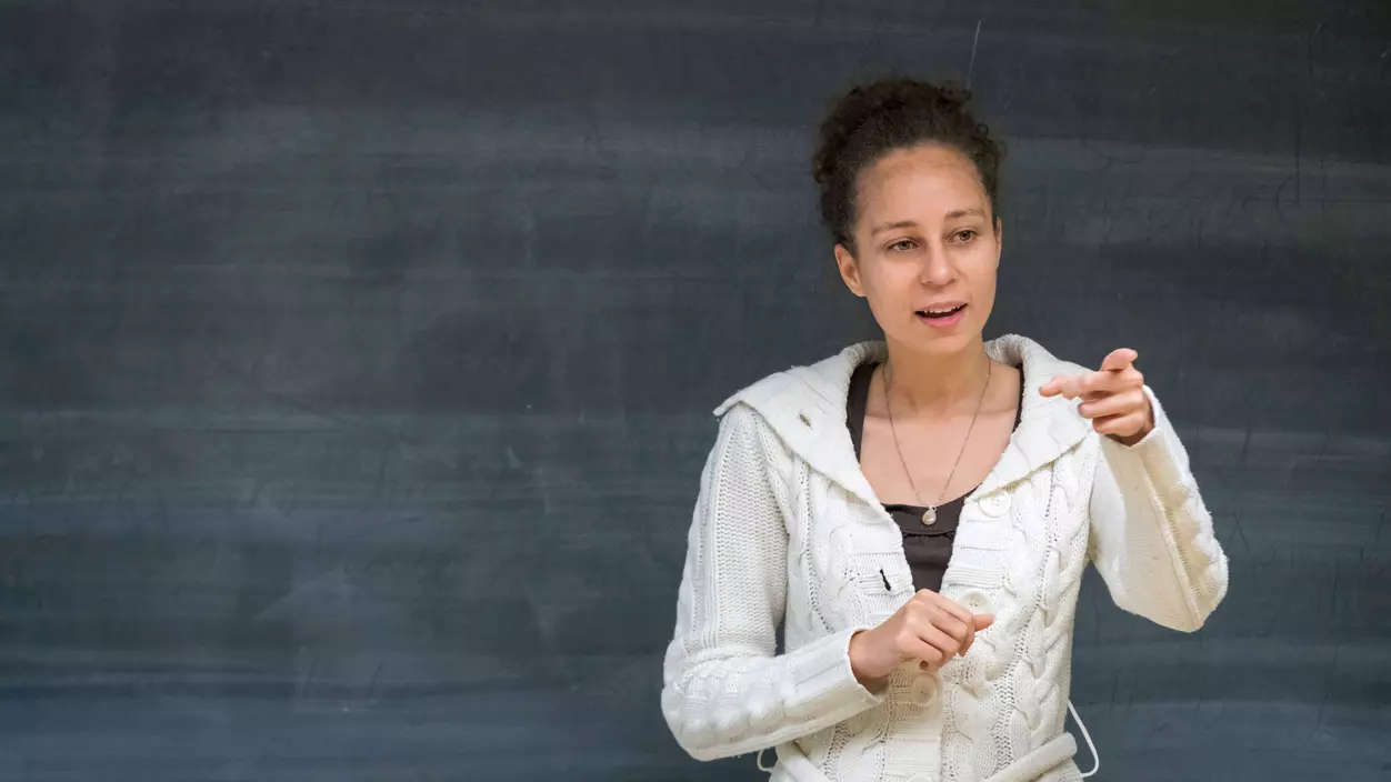 A person talking in front of a blackboard