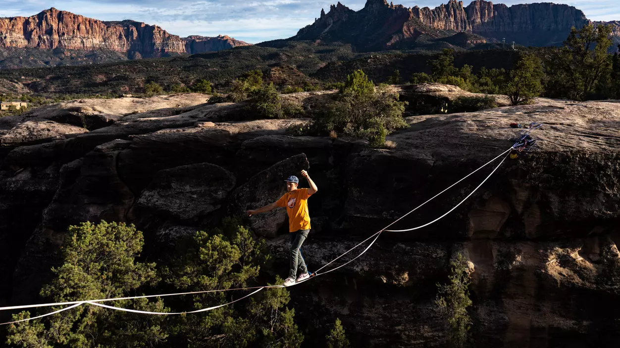 A person walking across a tightrope between two cliffs