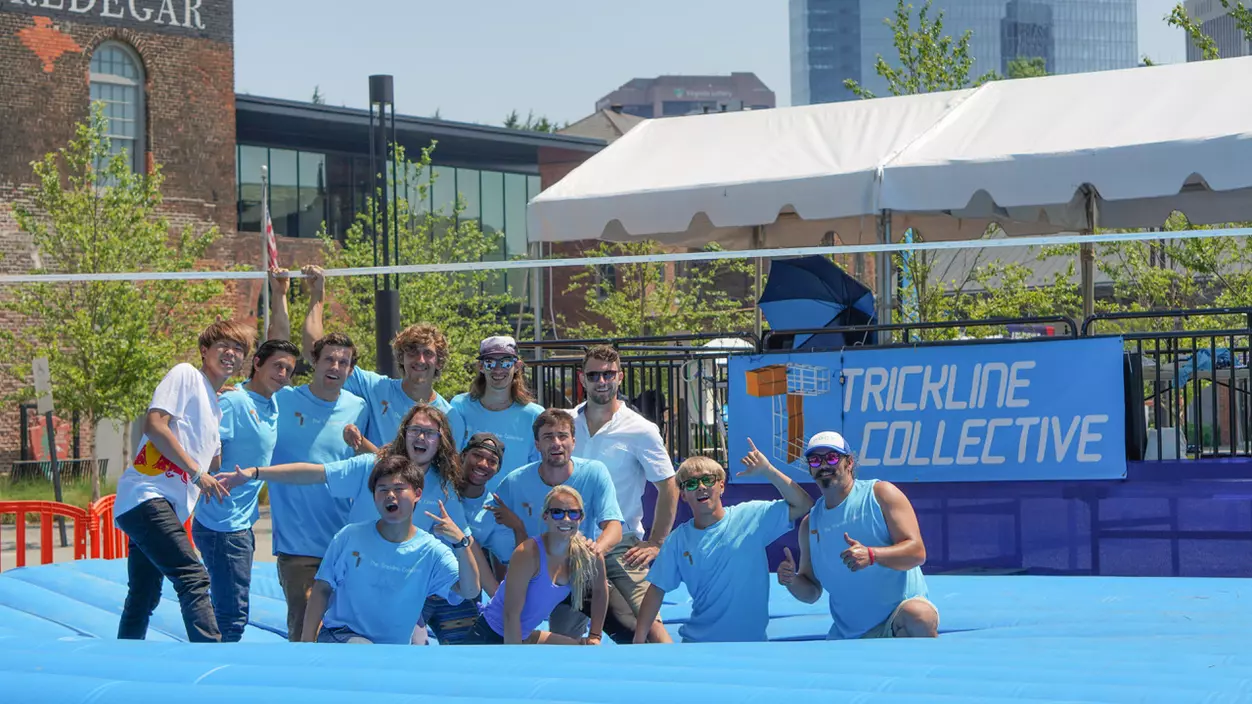 A group of people wearing blue shirts in front of a sign that says Trickline Collective