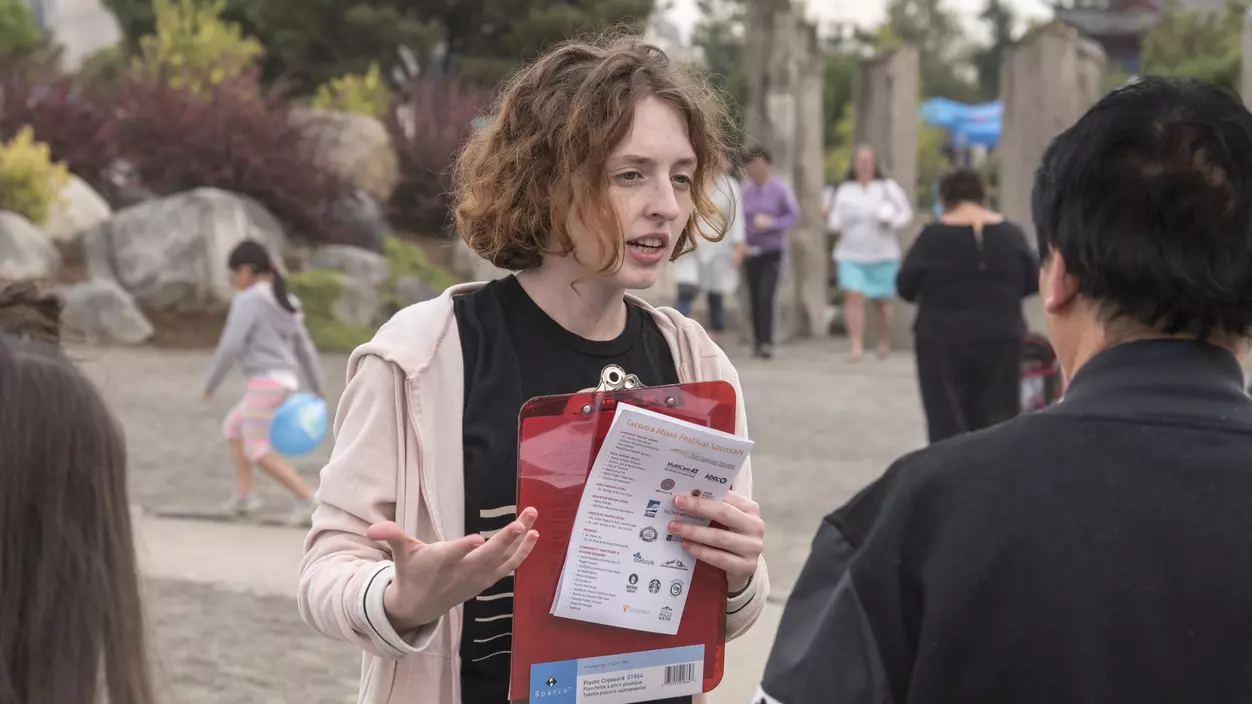 A person holding a clipboard talking to someone else