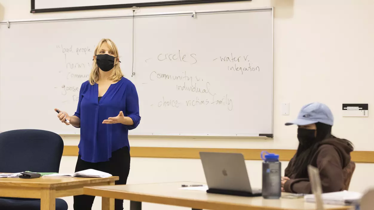 Tanya Erzen stands in front of a whiteboard, teaching