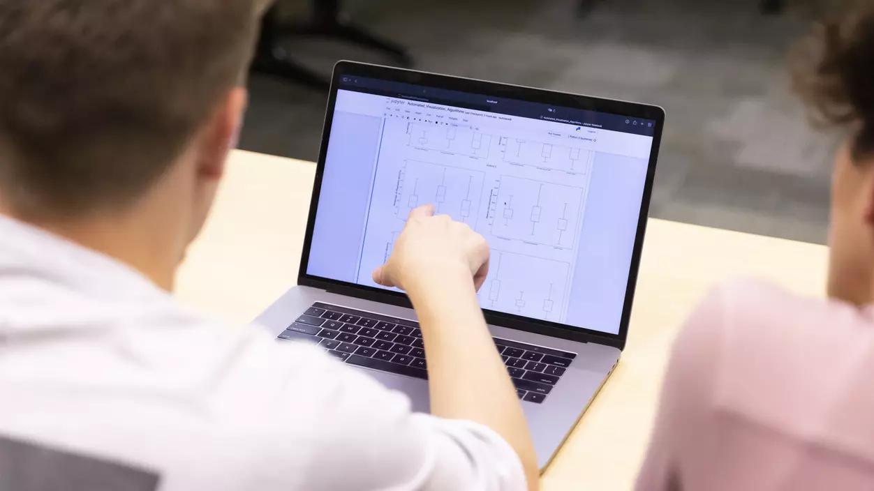 Looking over the shoulder of a student to see the screen of the student's laptop