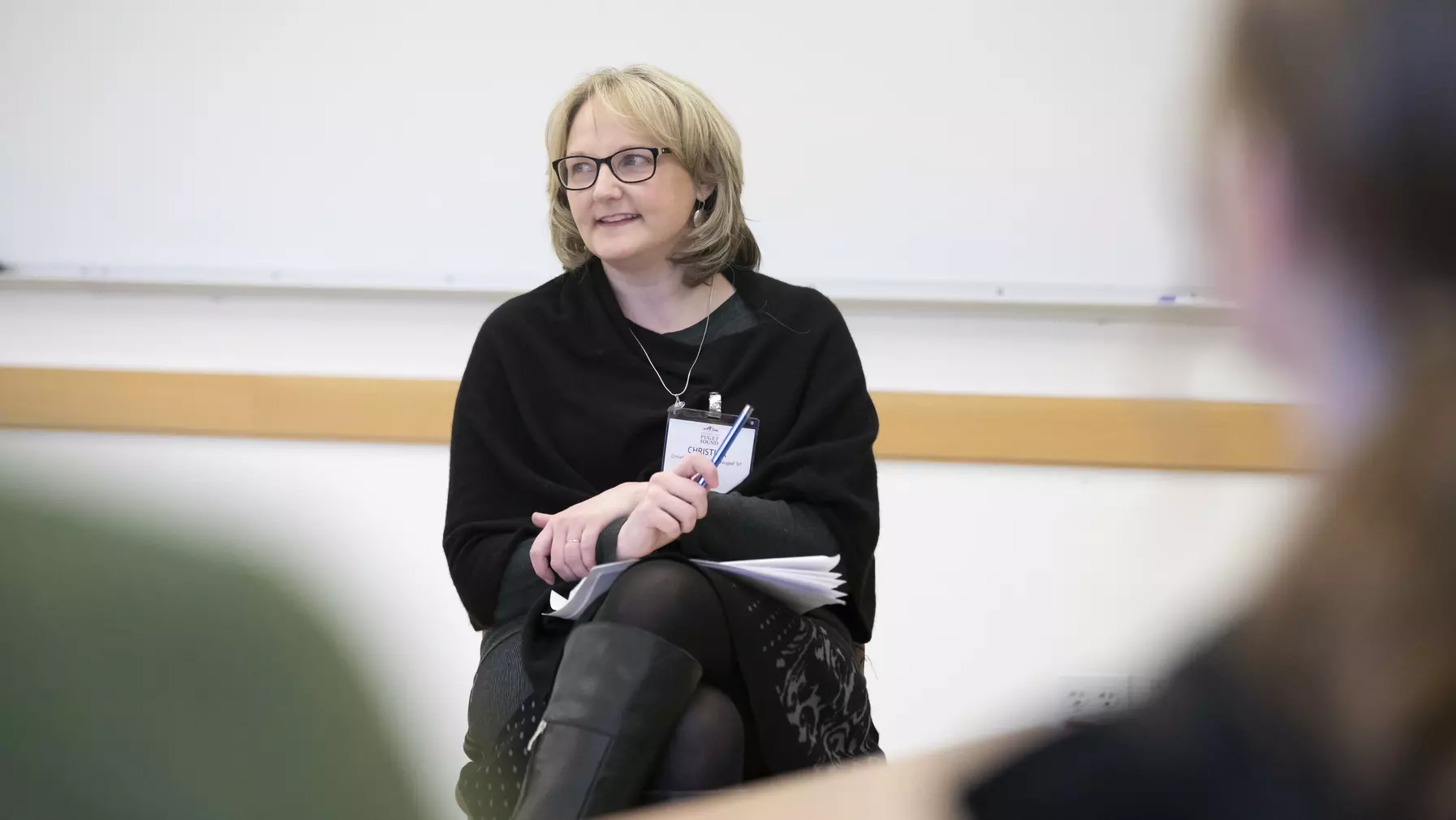 Woman wearing black sitting at the front of a classroom