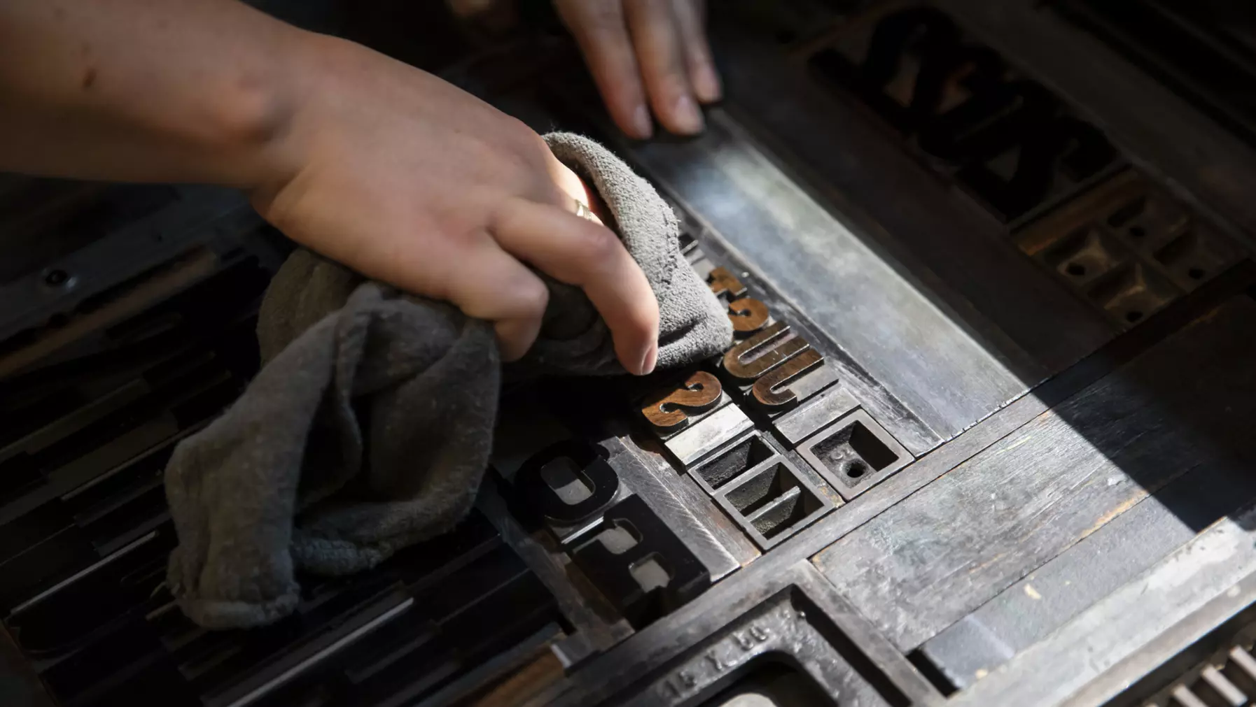 A person using a rag to clean metal letters