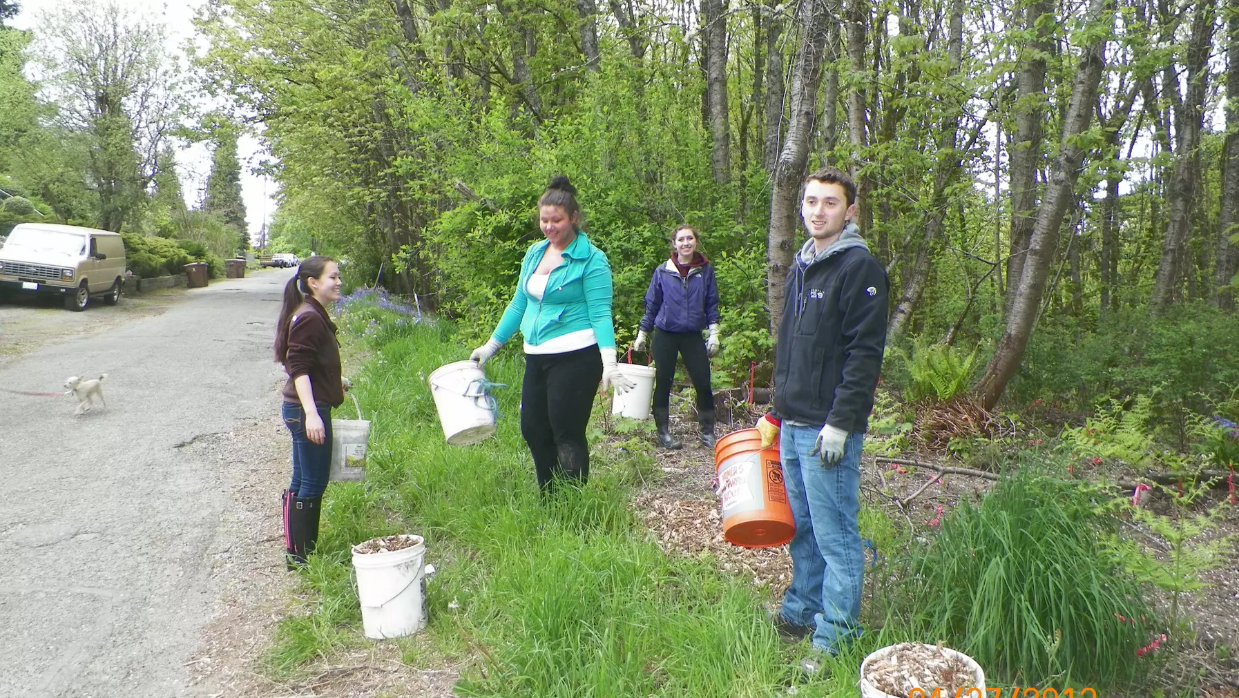 People holding buckets in a forest trail area