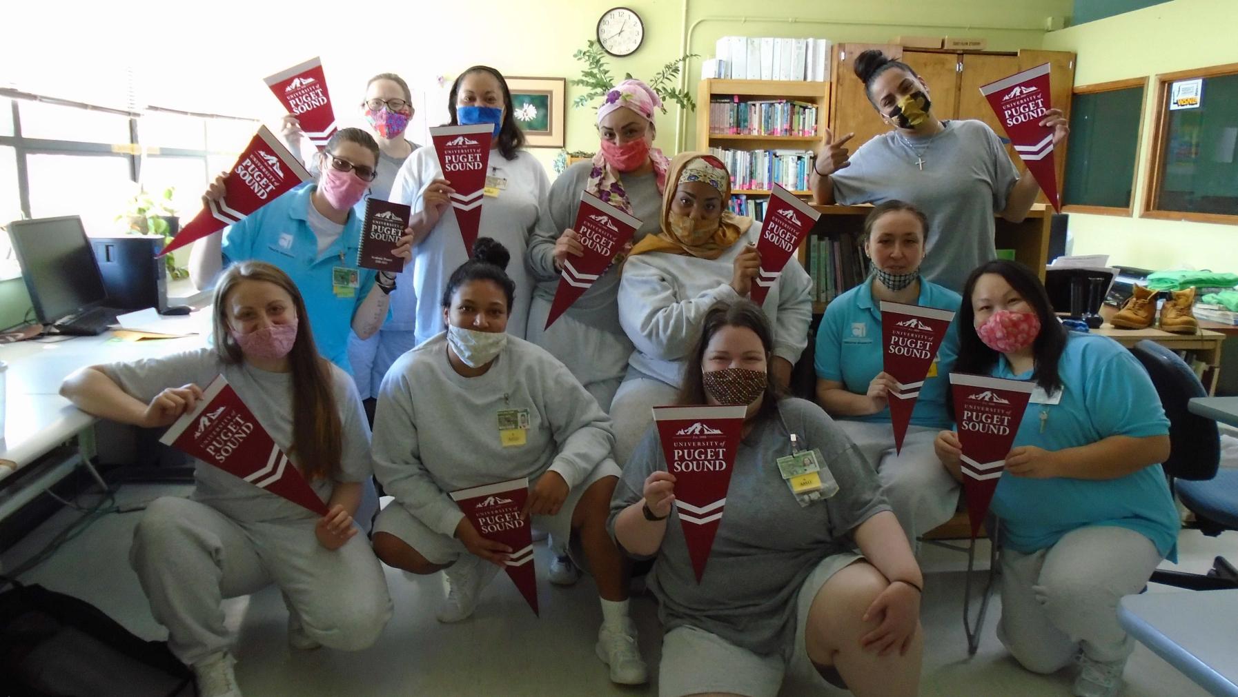 A group of people holding University of Puget Sound pennants