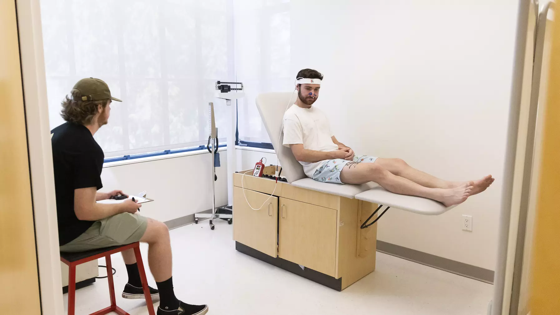 Graham Hall ’24 sits on an exam table while Chris Nicol ’24 asks questions.