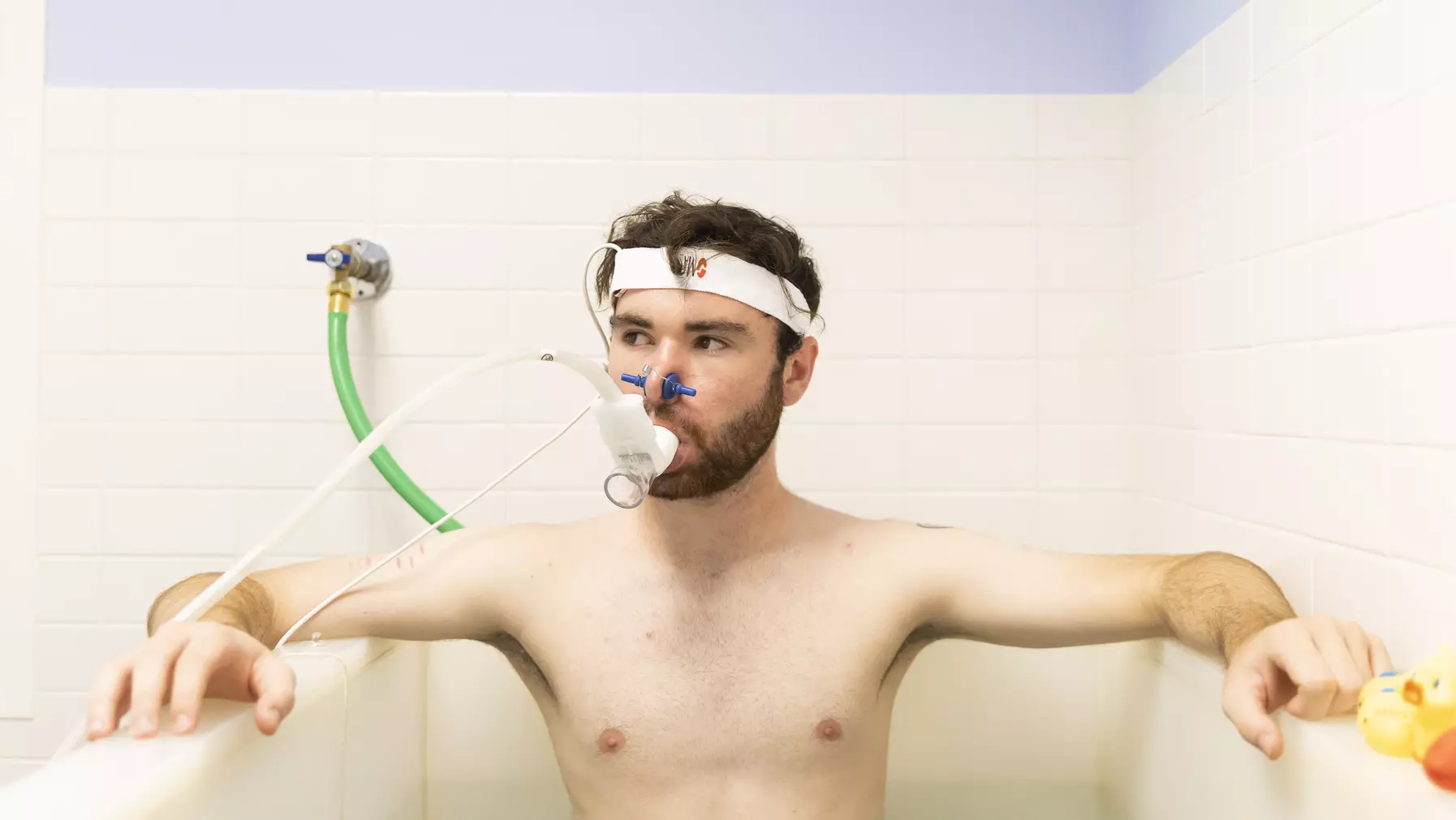 Graham Hall ’24 sits immersed up to his chest in a tub of water while wearing a headband which monitors his vitals and a breathing apparatus.